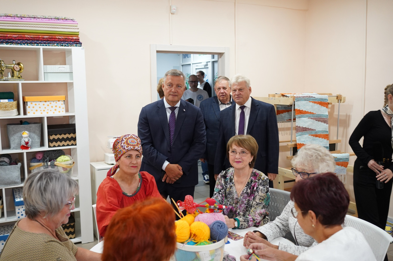 Группа людей обсуждает рукоделие в мастерской.
