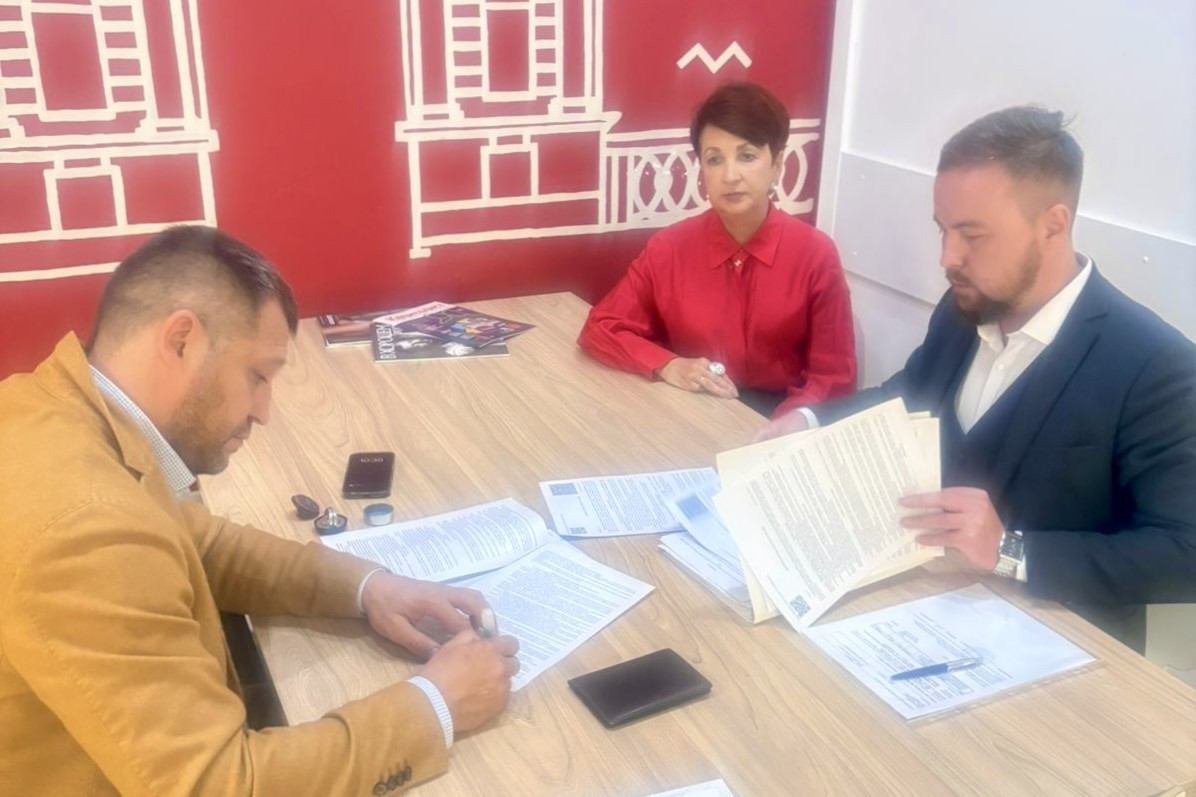 Три человека обсуждают документы за столом.