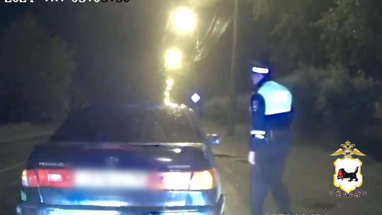 Полицейский останавливает машину ночью.