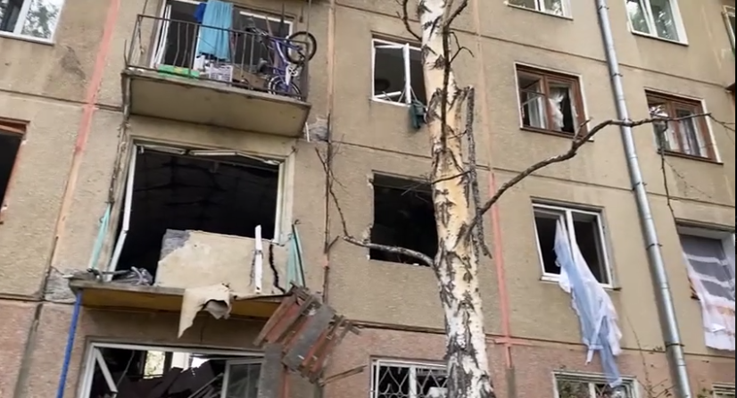 Повреждённое здание с выбитыми окнами и балконом.