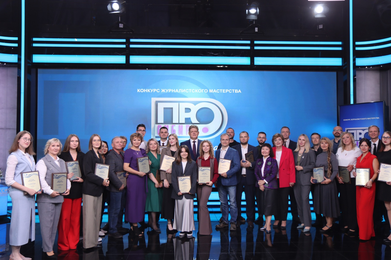 Группа людей с наградами на конкурсе журналистики.