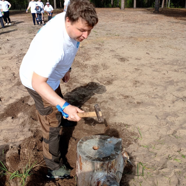 Человек с молотком у пня на улице