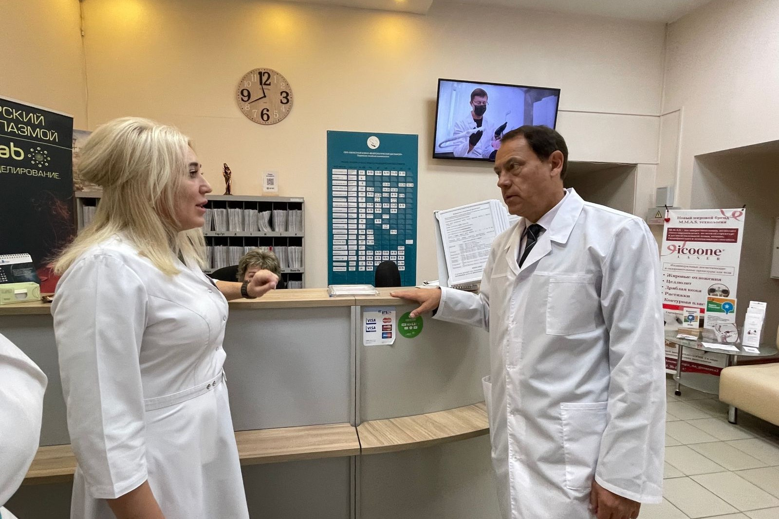 Врачи обсуждают у стойки ресепшн в клинике.