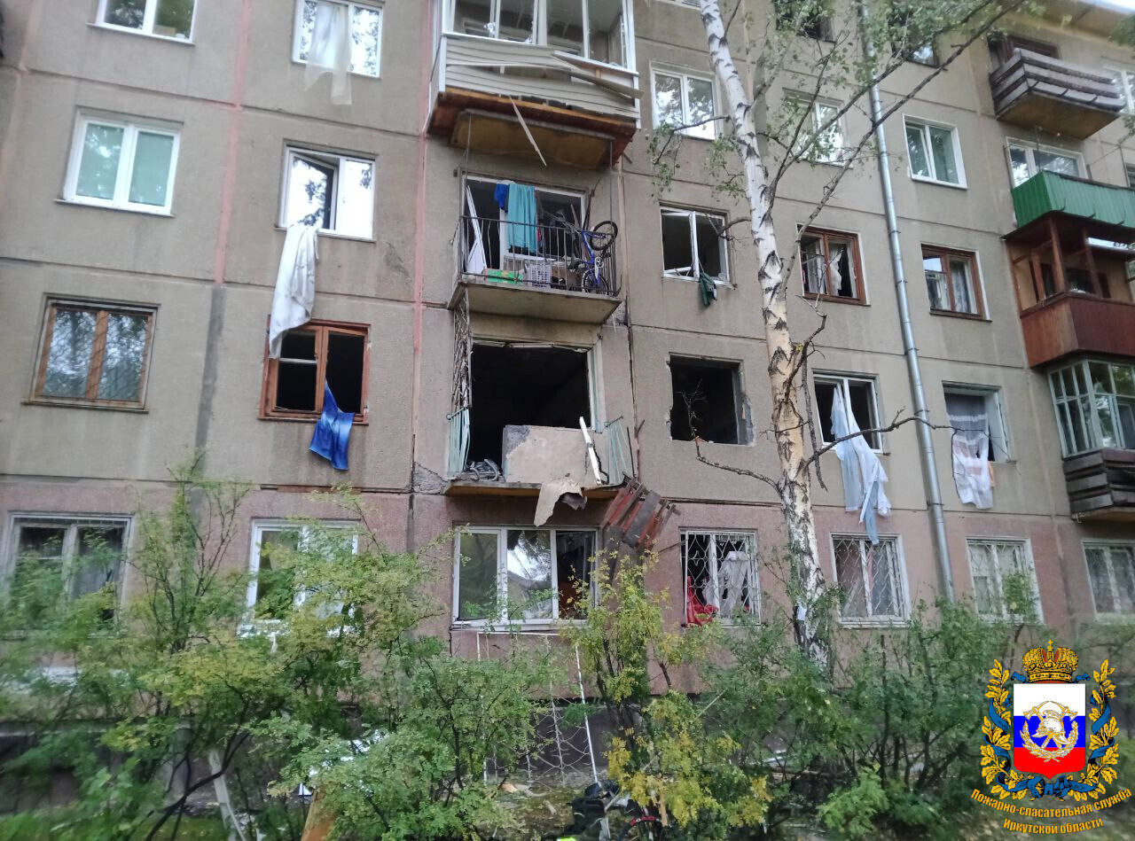 Многоэтажный дом с выбитыми окнами и балконами.
