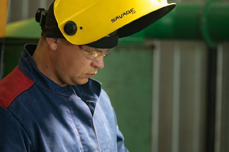 Человек в защитной каске и очках на работе.