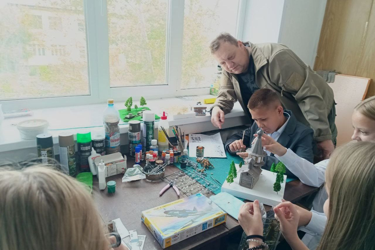 Дети собирают модели под руководством наставника в классе.