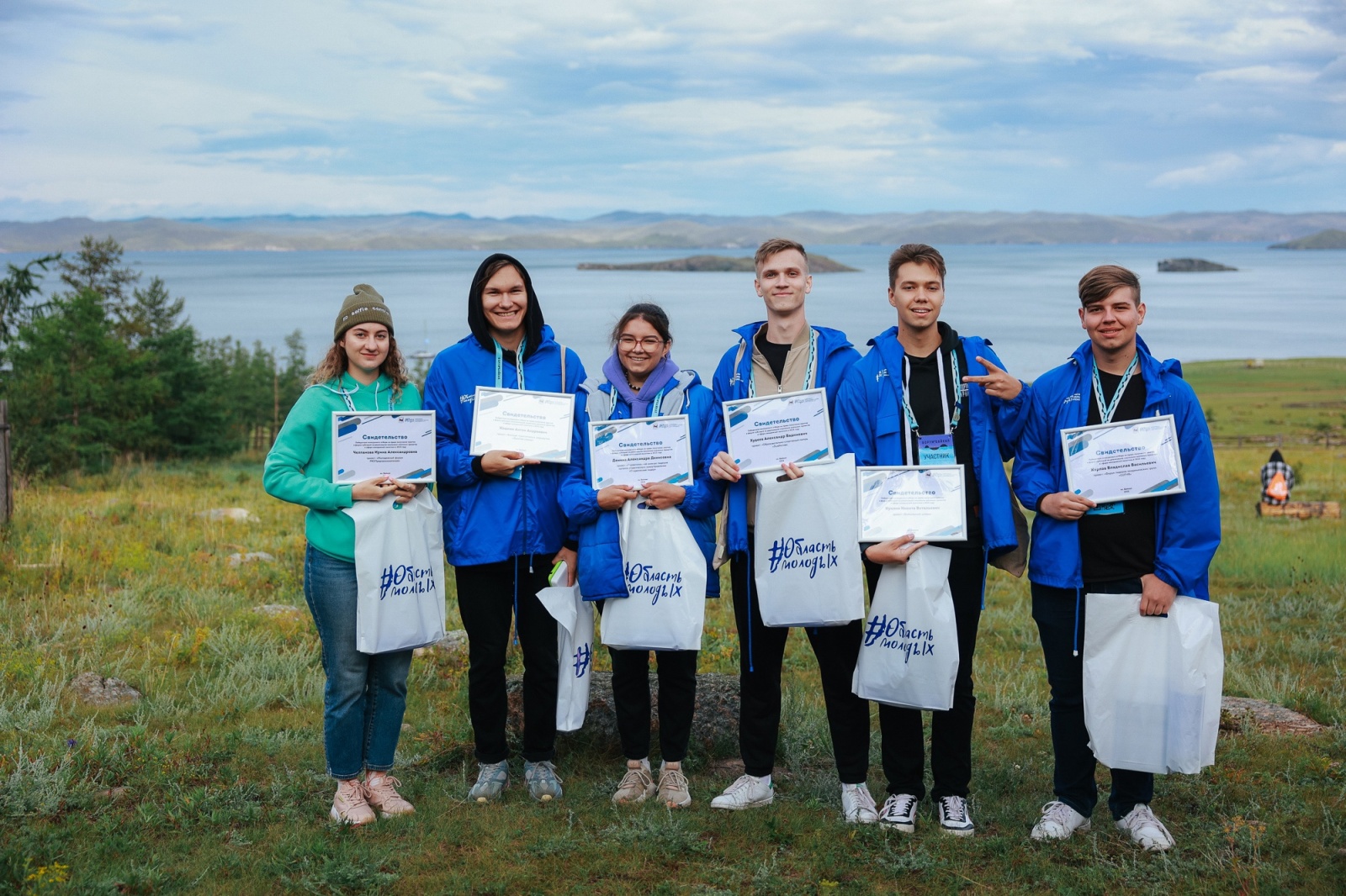Молодые люди с сертификатами на берегу озера