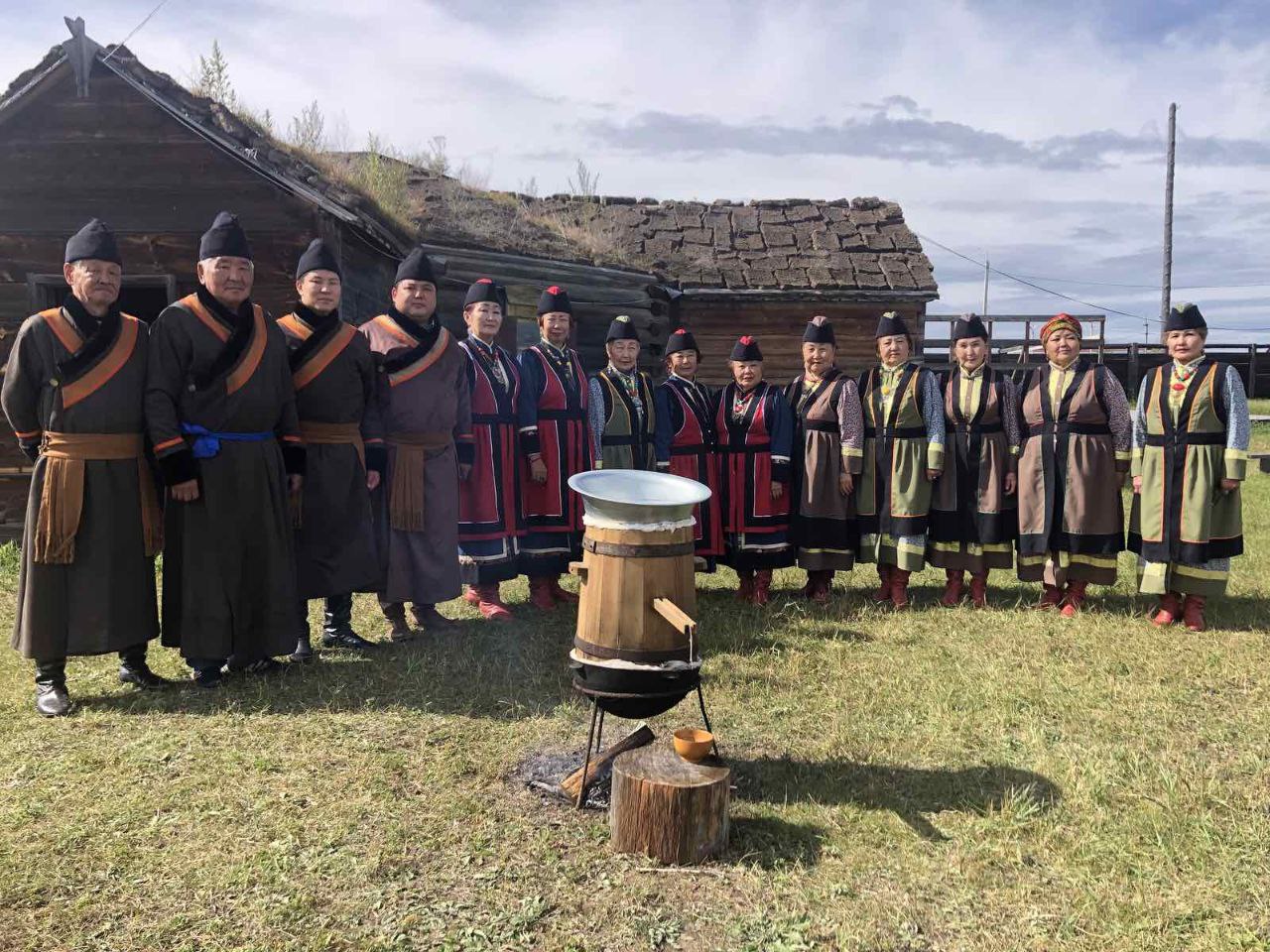 Люди в национальных костюмах на фоне деревянных домов.