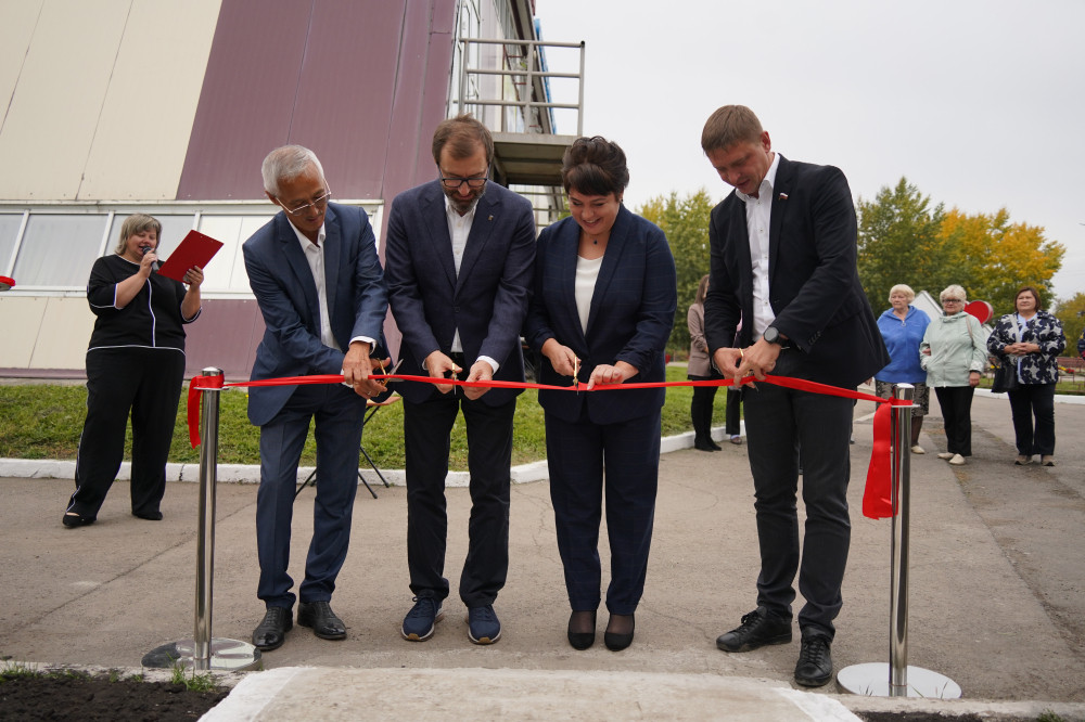 Люди перерезают красную ленту на церемонии открытия.