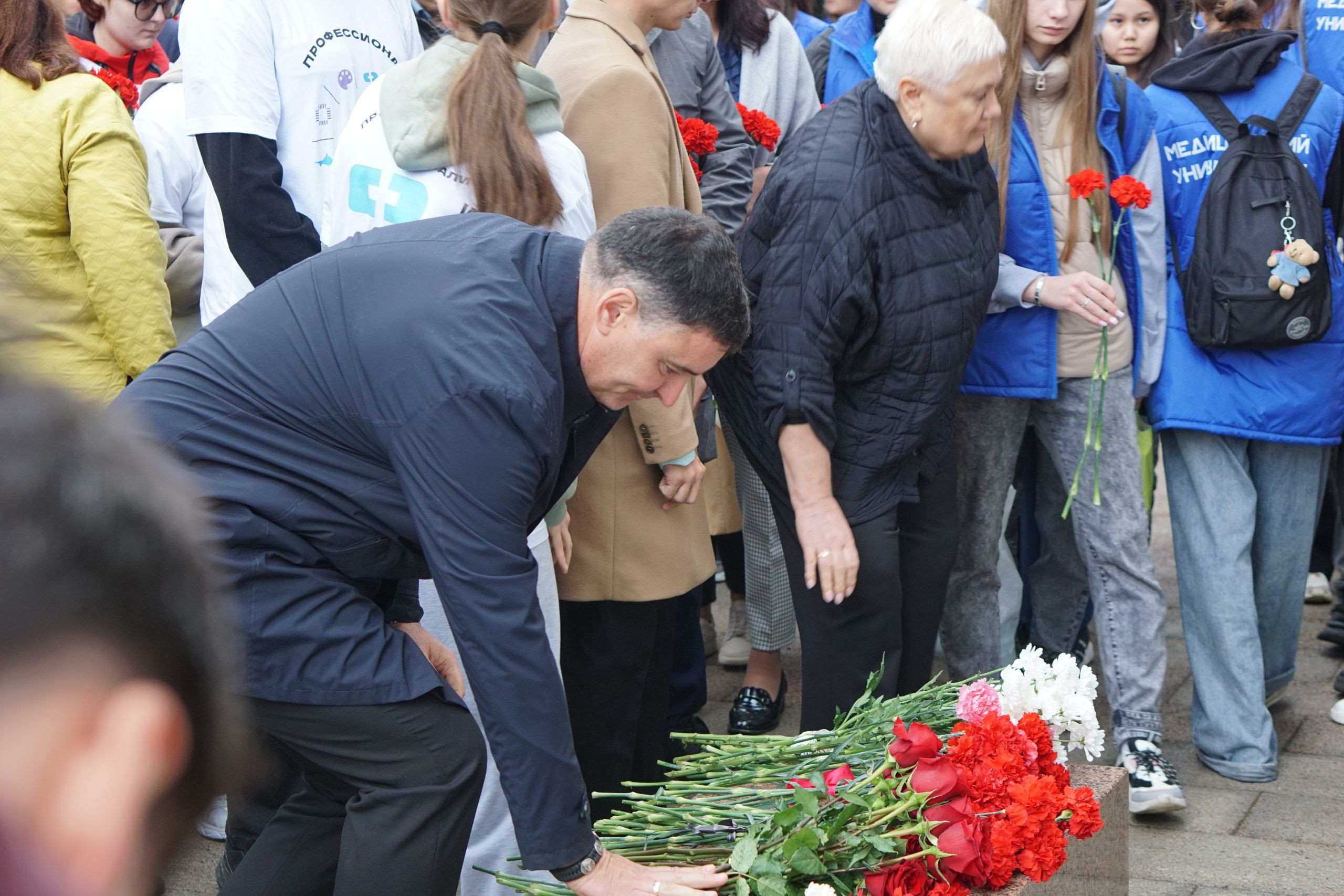 Люди кладут цветы к мемориалу в память.