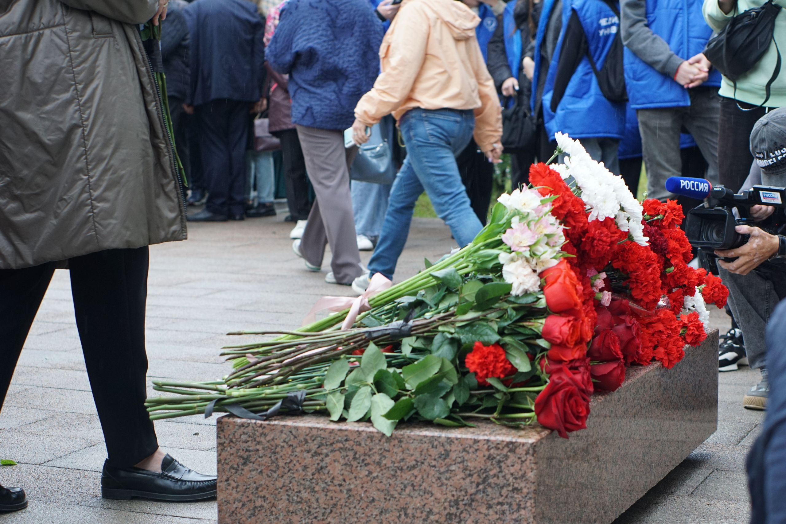 Люди возлагают цветы к памятнику.