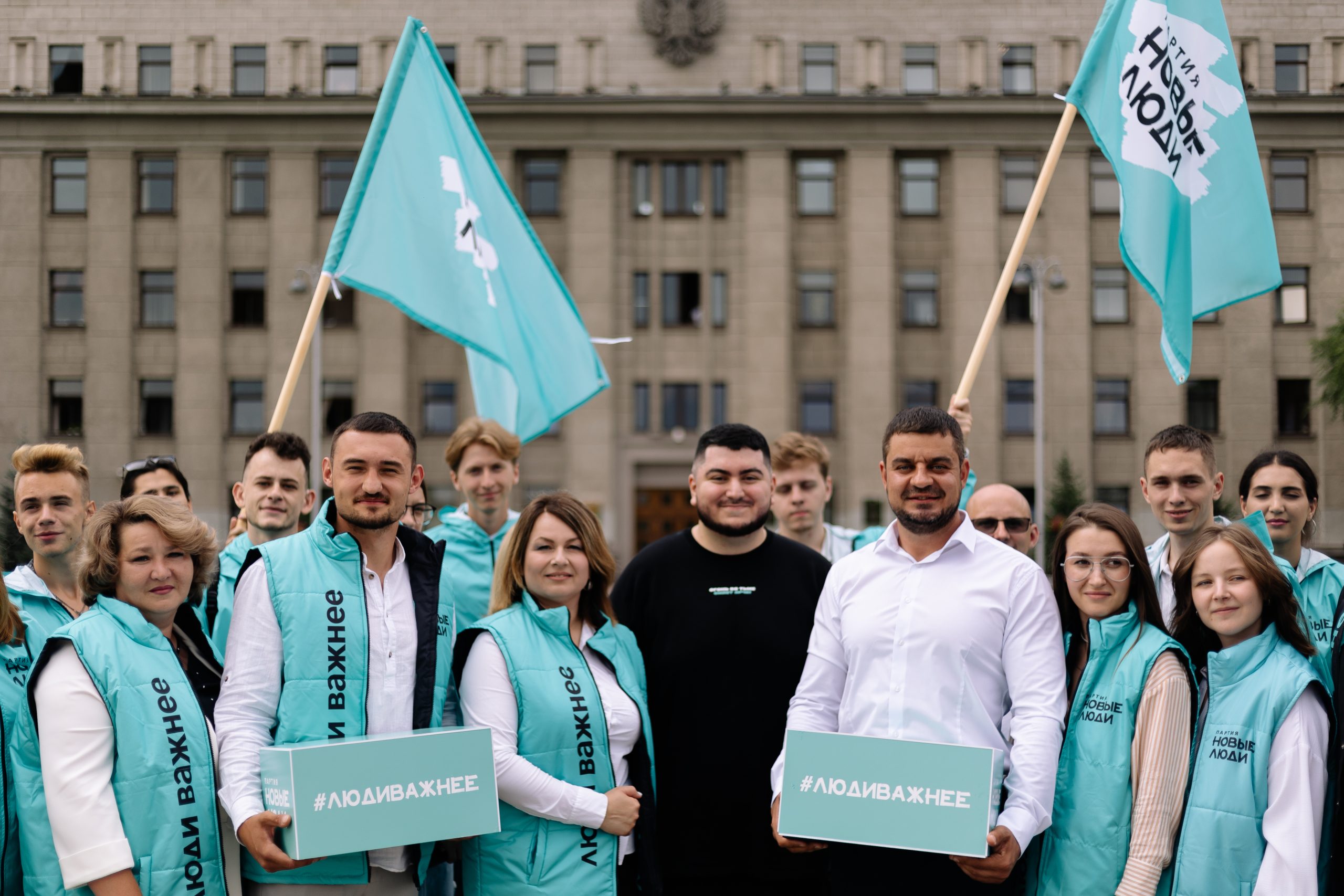 Группа людей с плакатами и флагом на улице.