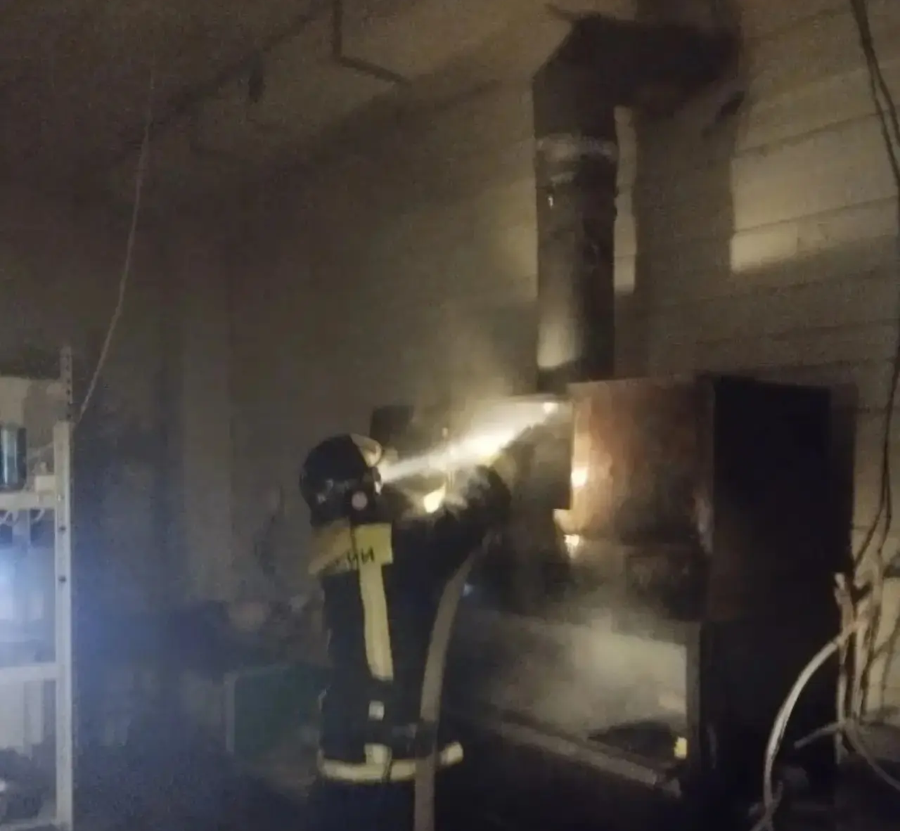 Пожарный тушит пожар в здании