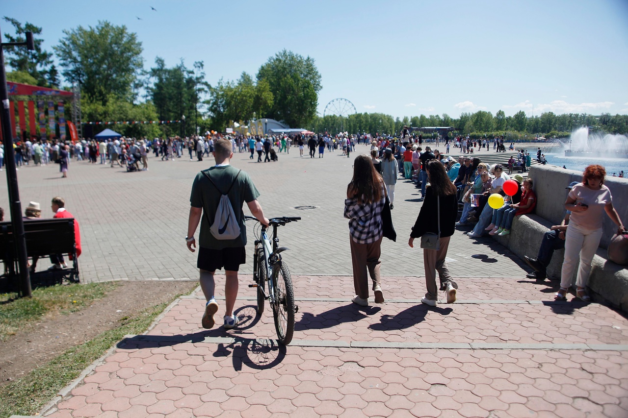Солнечный день в парке Иркутска: люди гуляют, фонтан, деревья, колесо обозрения.