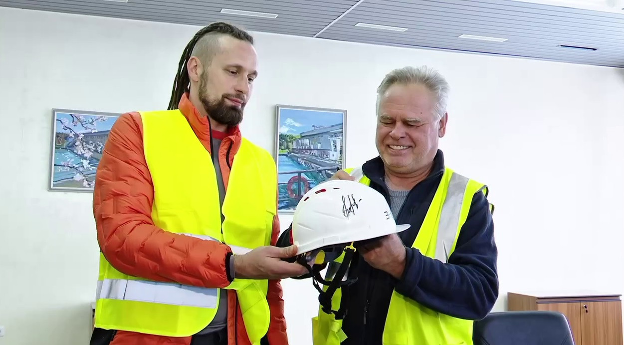 Два рабочих показывают каску с автографом