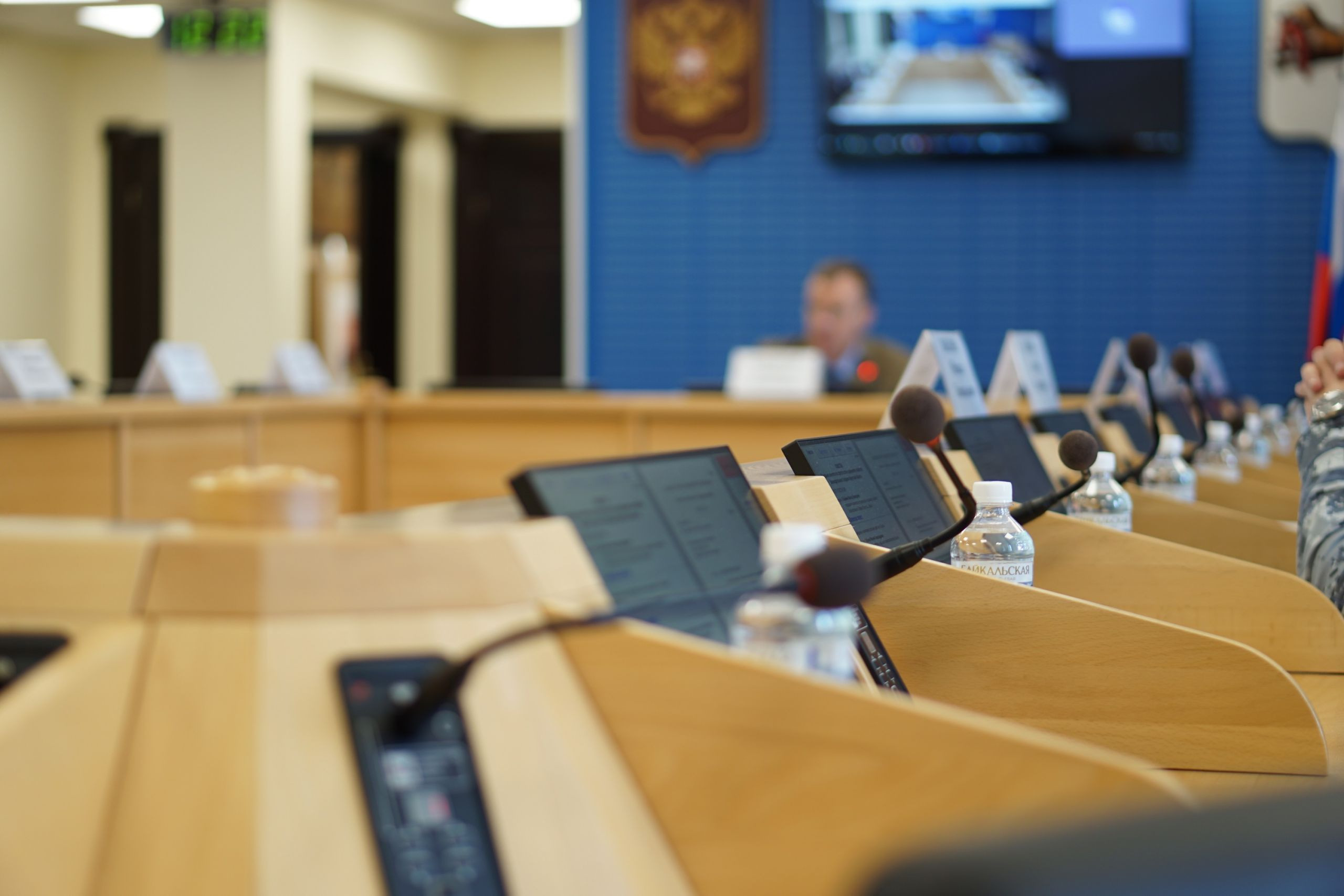 Микрофоны и планшеты в конференц-зале, фокус на столе.