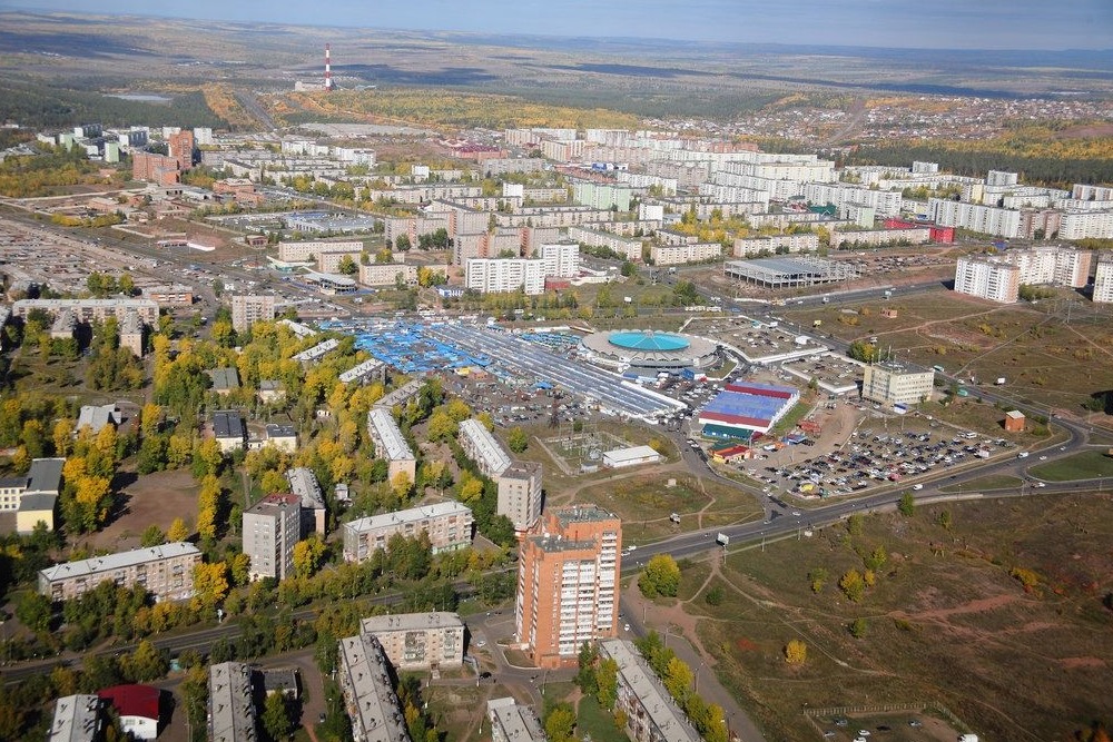 Панорама города с высоты, много зелени.