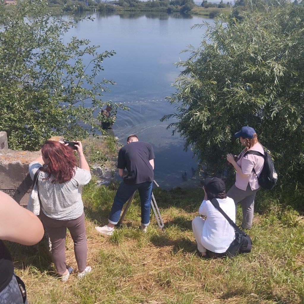 Люди фотографируют озеро и природу.