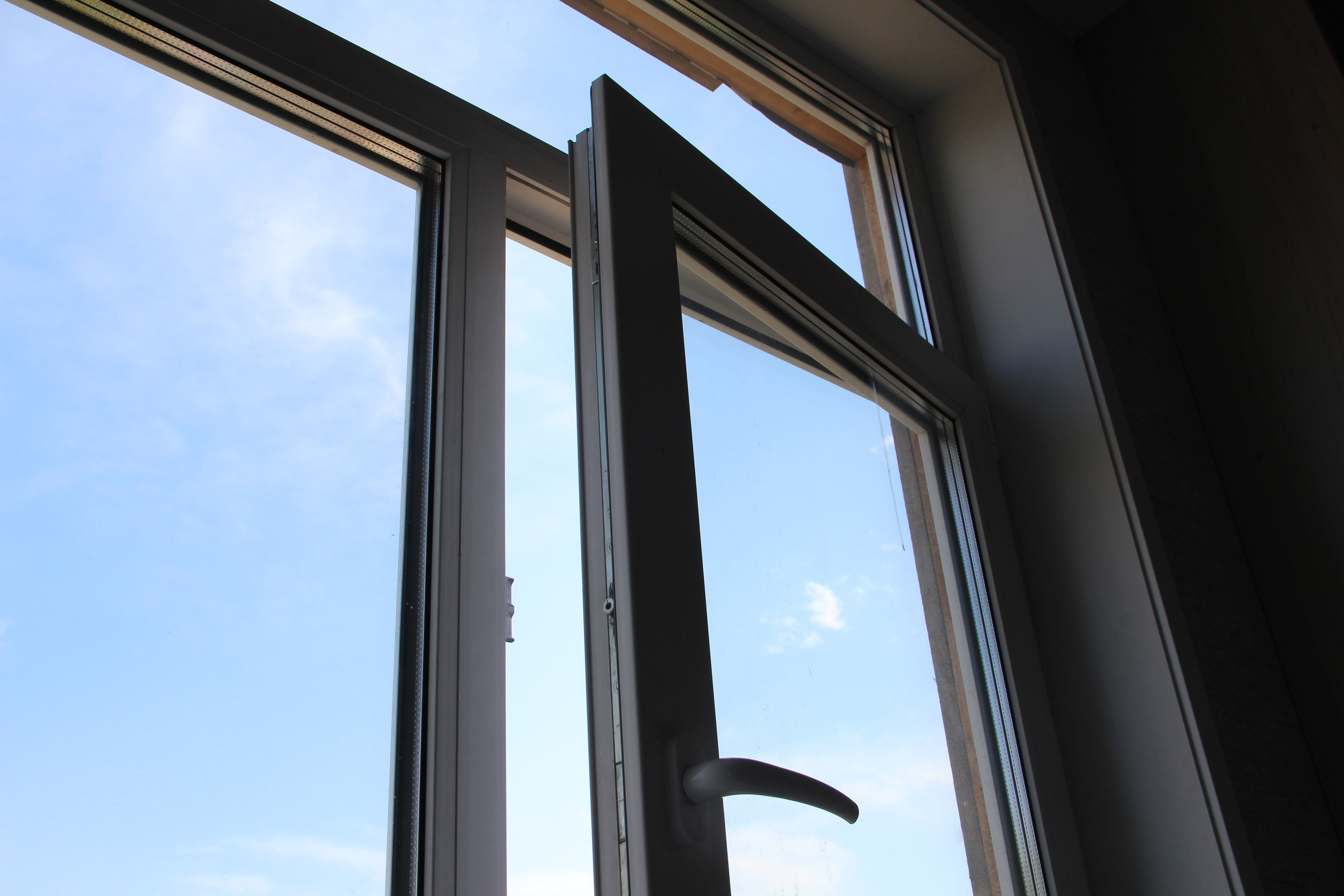 Открытое пластиковое окно на фоне голубого неба