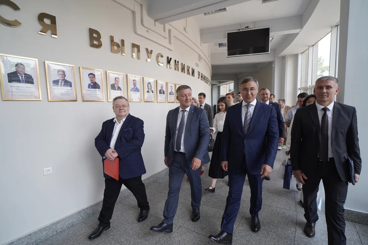 Группа мужчин осматривает стену выпускников.