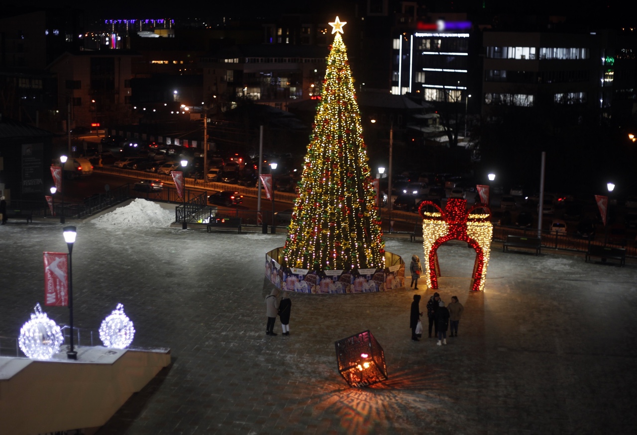 Новогодняя елка с огнями на городской площади ночью.