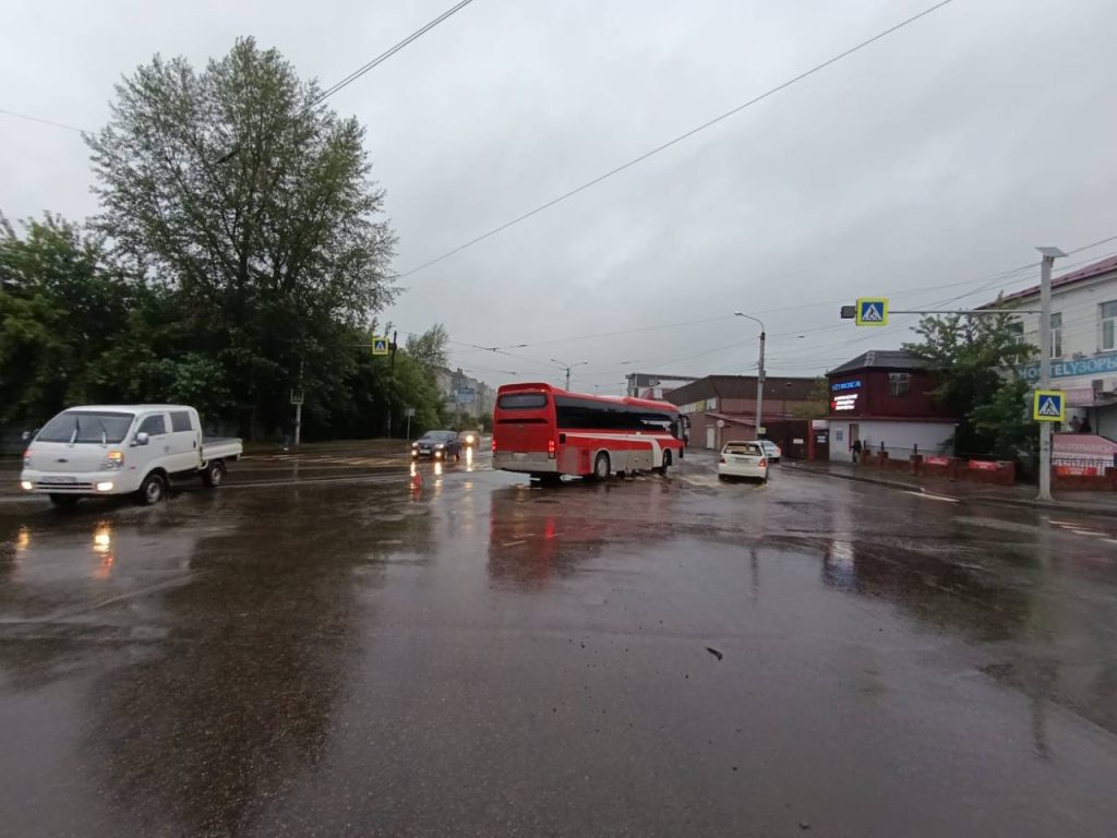 Городская улица с дождем, машины и автобус.