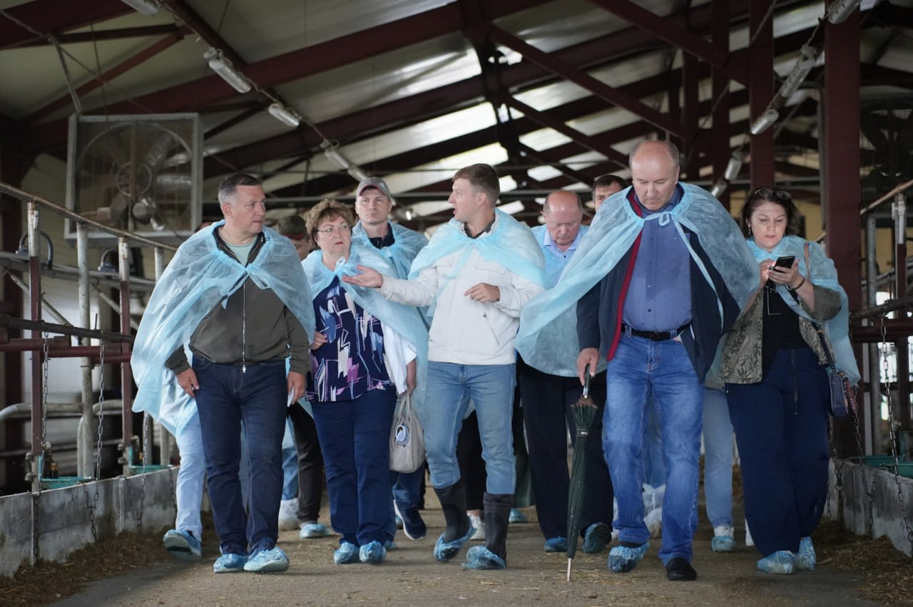 Группа людей в защитных халатах на ферме
