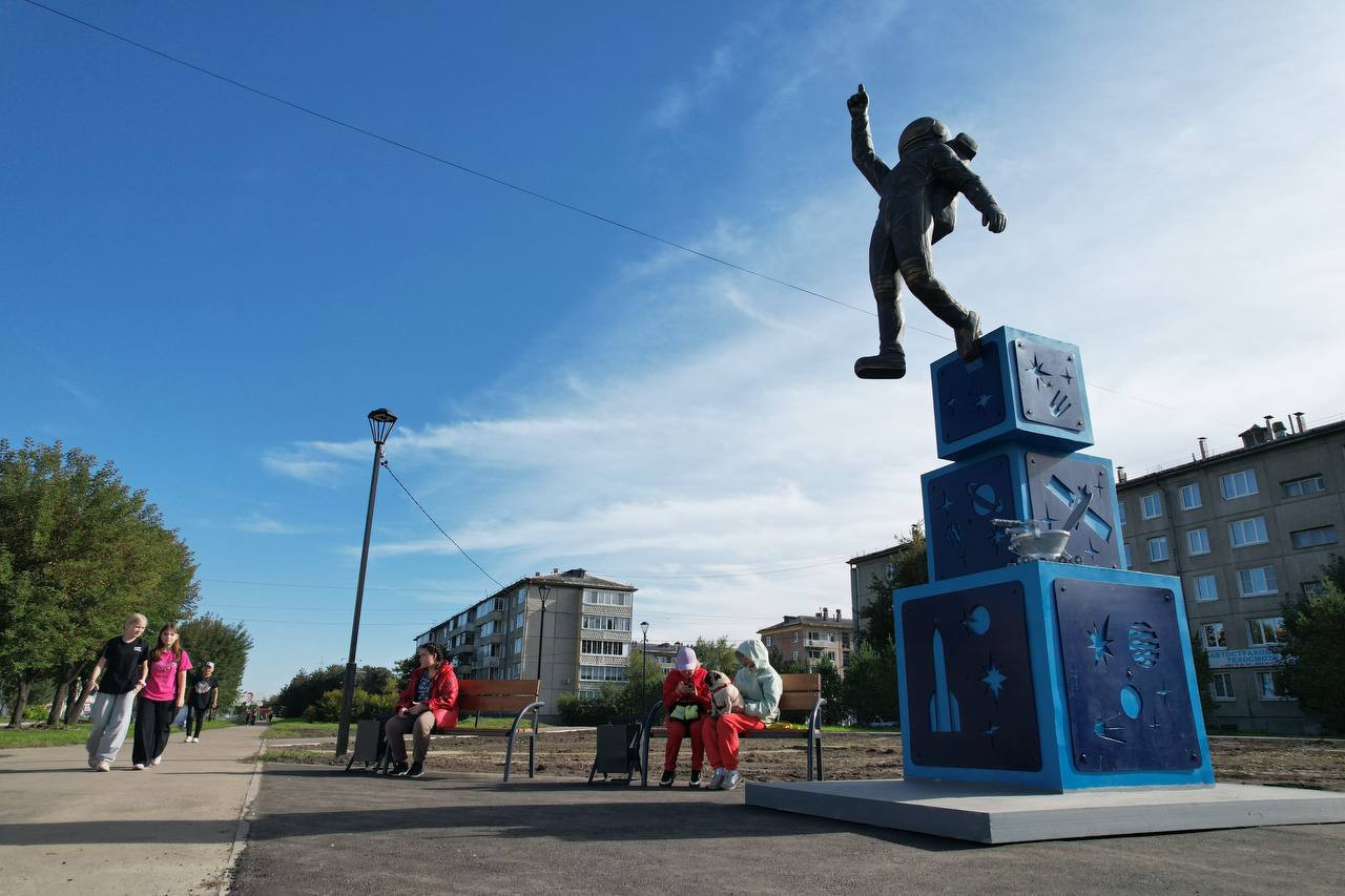 Монумент космонавта на улице с людьми.