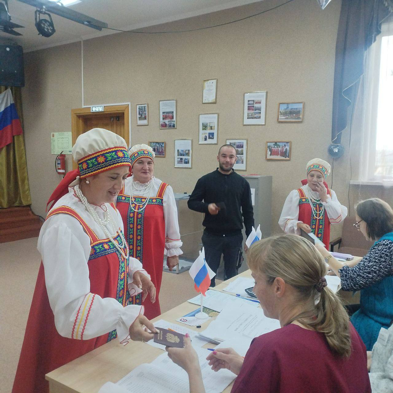 Женщины в народных костюмах голосуют на выборах.