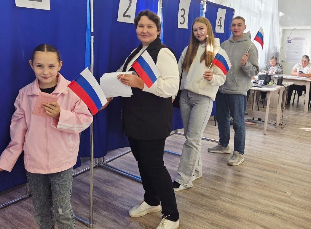 Люди с флагами голосуют в избирательном участке.