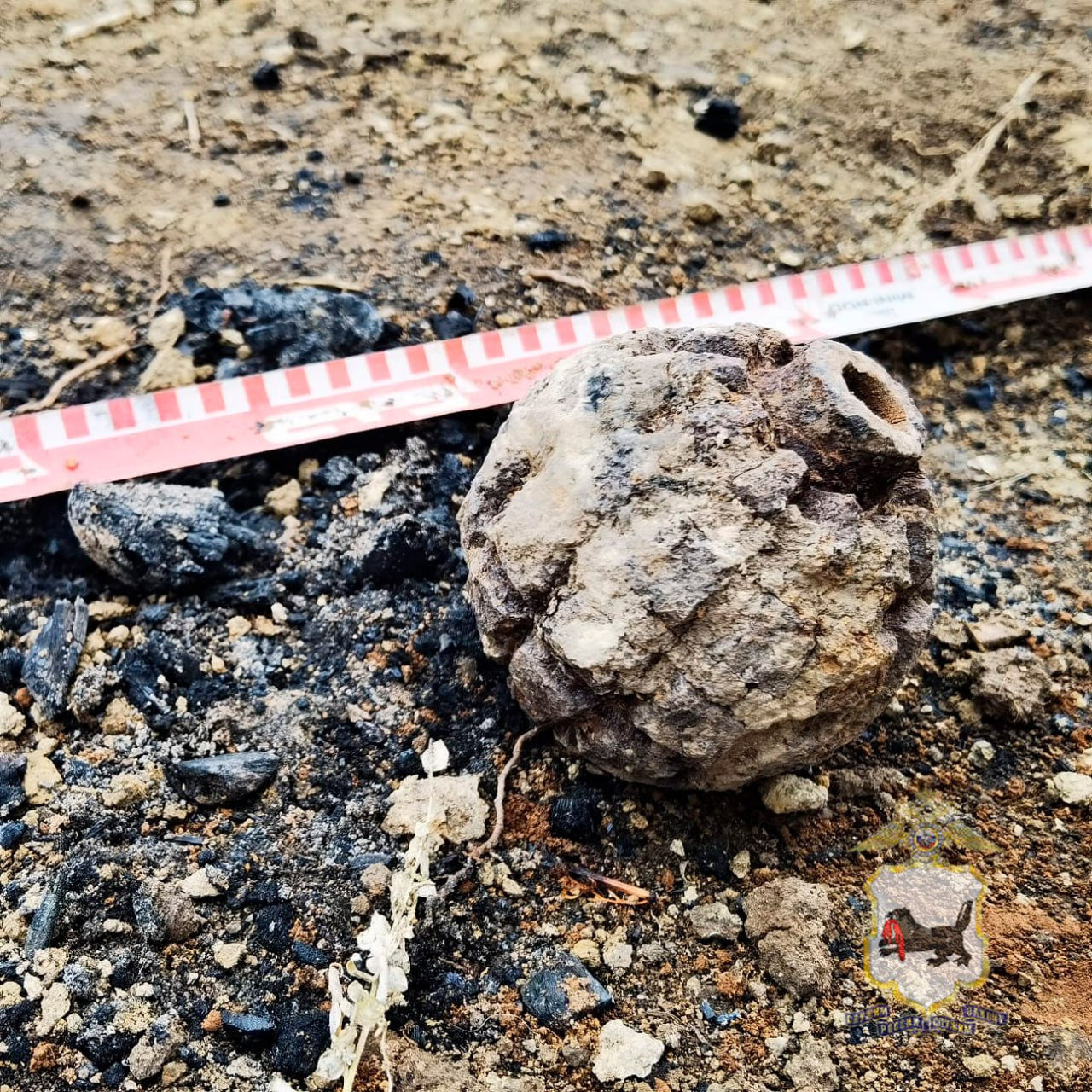 Старая граната на земле возле измерительной ленты.