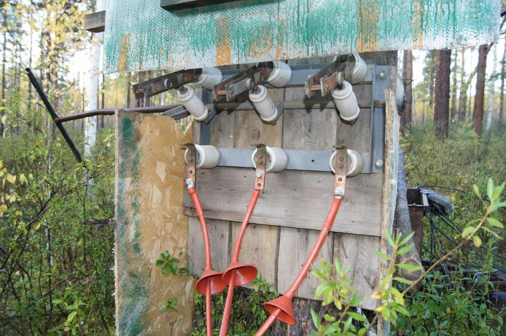 Старая электропанель с керамическими предохранителями в лесу.