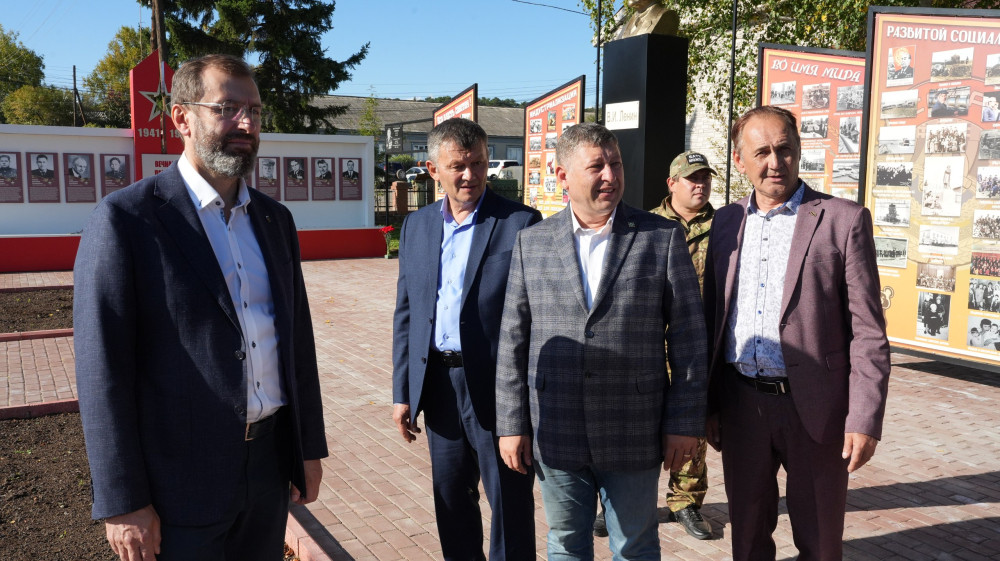 Мужчины у стенда памятника на улице.