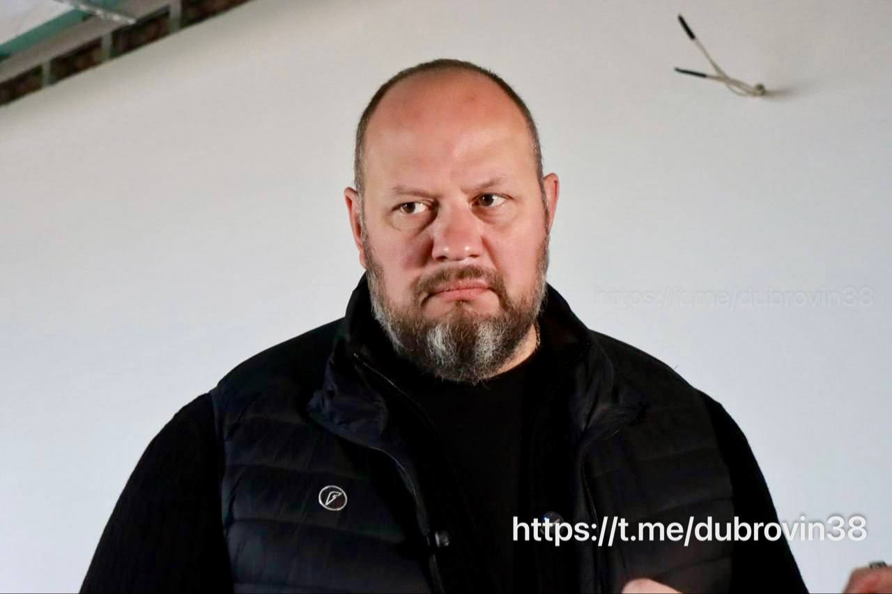 Мужчина в черной куртке, серьезное выражение лица.