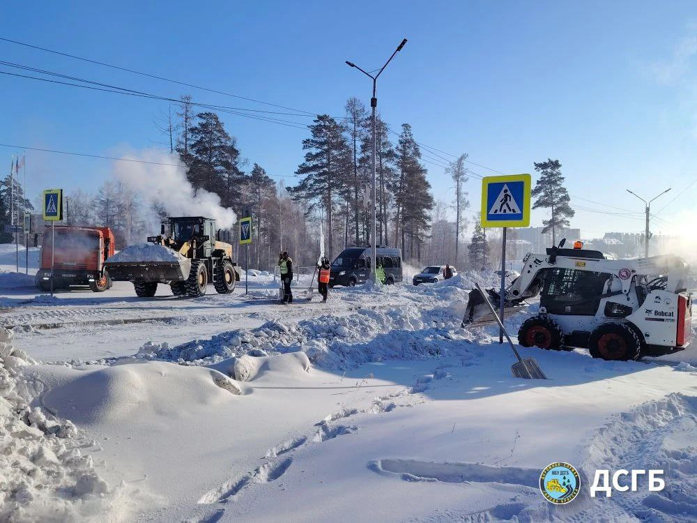 Уборка снега на дороге спецтехникой зимой.