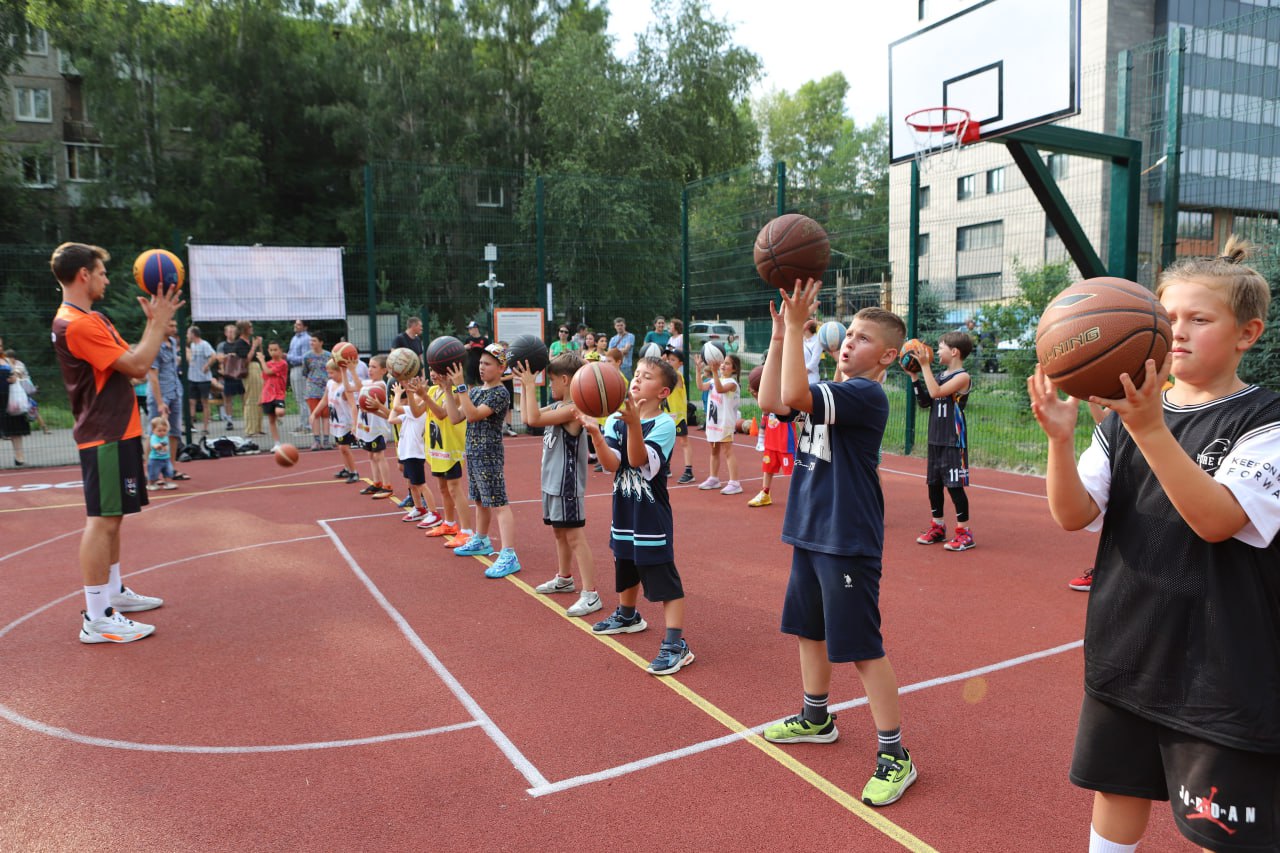 Дети учатся баскетболу на открытой площадке