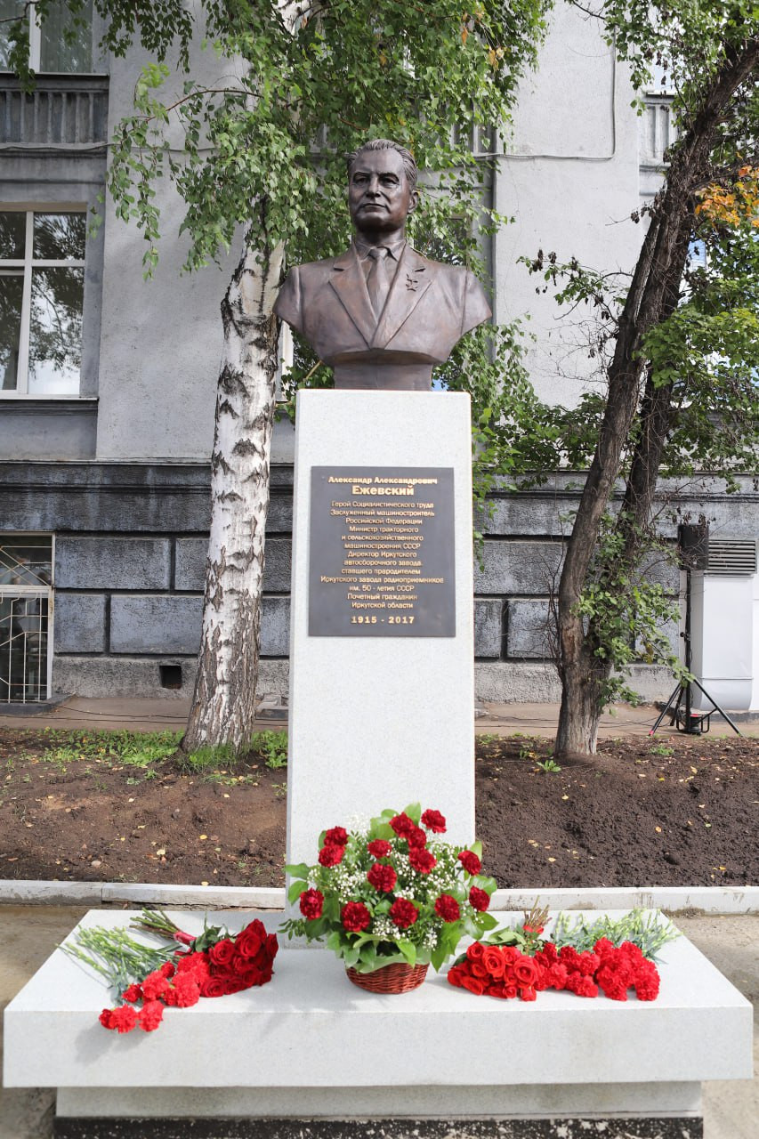 Бюст и цветы на памятнике возле здания