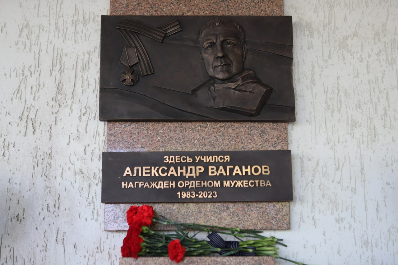 Мемориальная доска с портретом и гвоздиками.