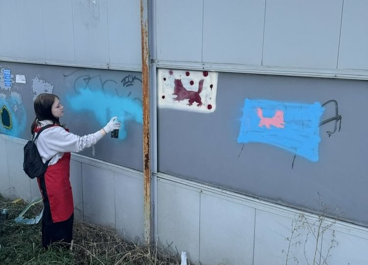 Человек рисует граффити на стене.