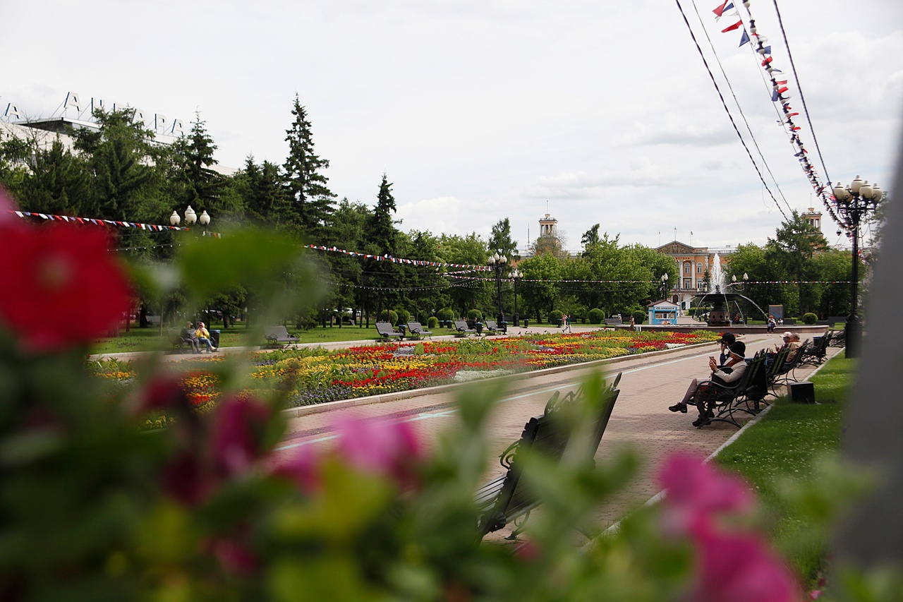 Парк с цветочными клумбами и скамейками.