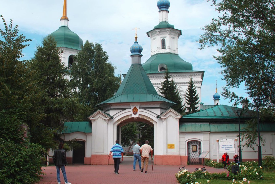 Монастырь с зелёными куполами и воротами, люди идёт.