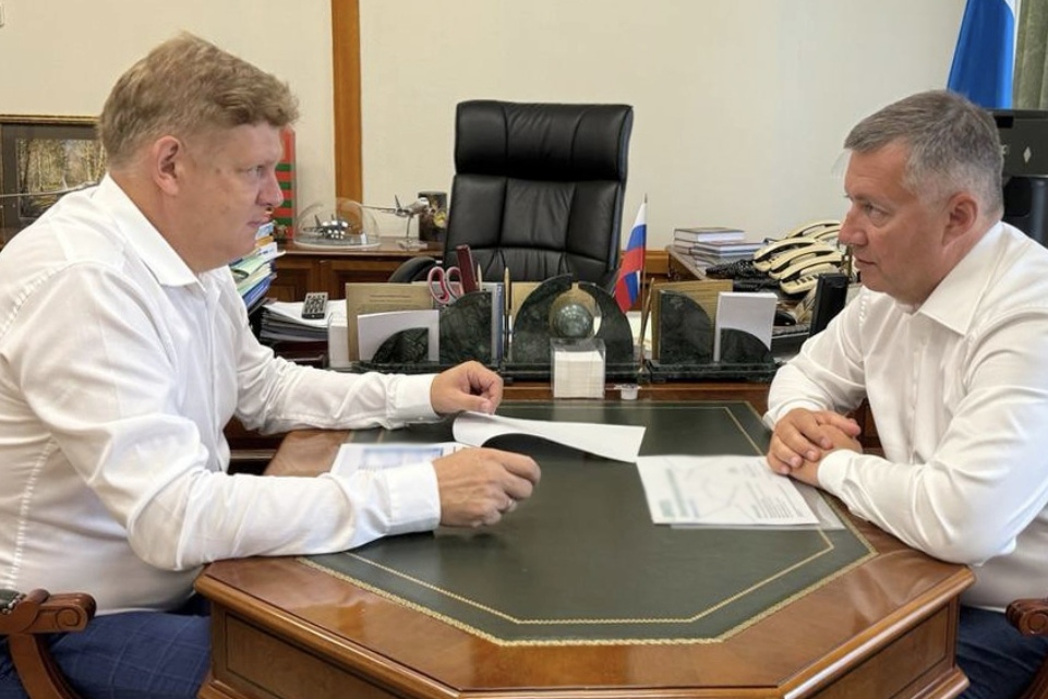 Двое мужчин обсуждают документы за столом.