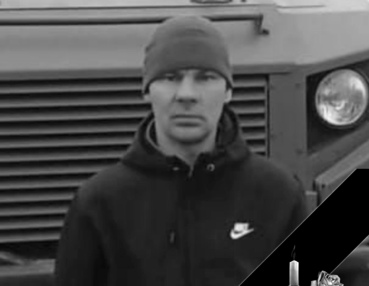 Мужчина в шапке перед машиной, свеча и цветы