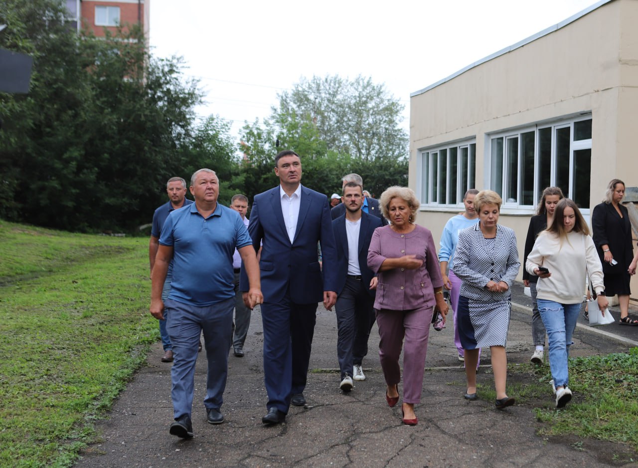 Группа людей гуляет на улице возле здания.