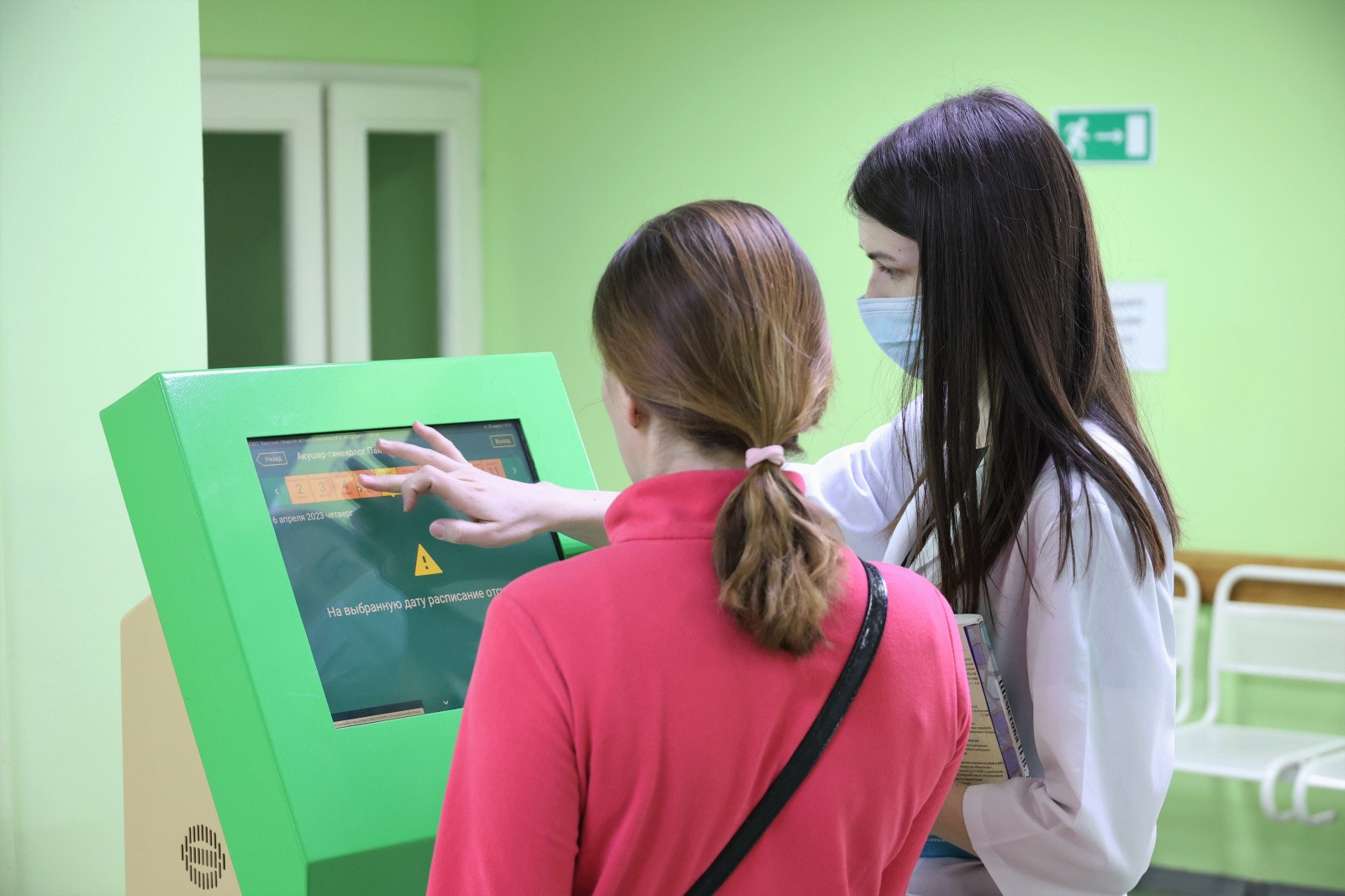 Женщина помогает выбрать дату на зеленом терминале.